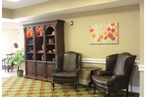 A cozy lounge area with leather chairs and a decorated bookshelf.