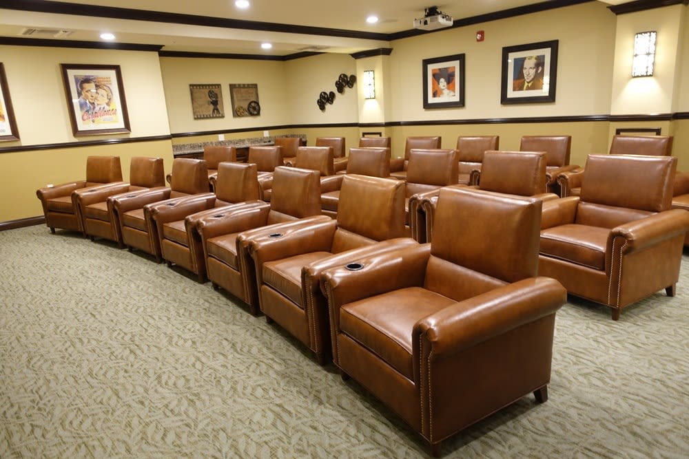 A luxurious home theater room featuring rows of brown leather recliner chairs.