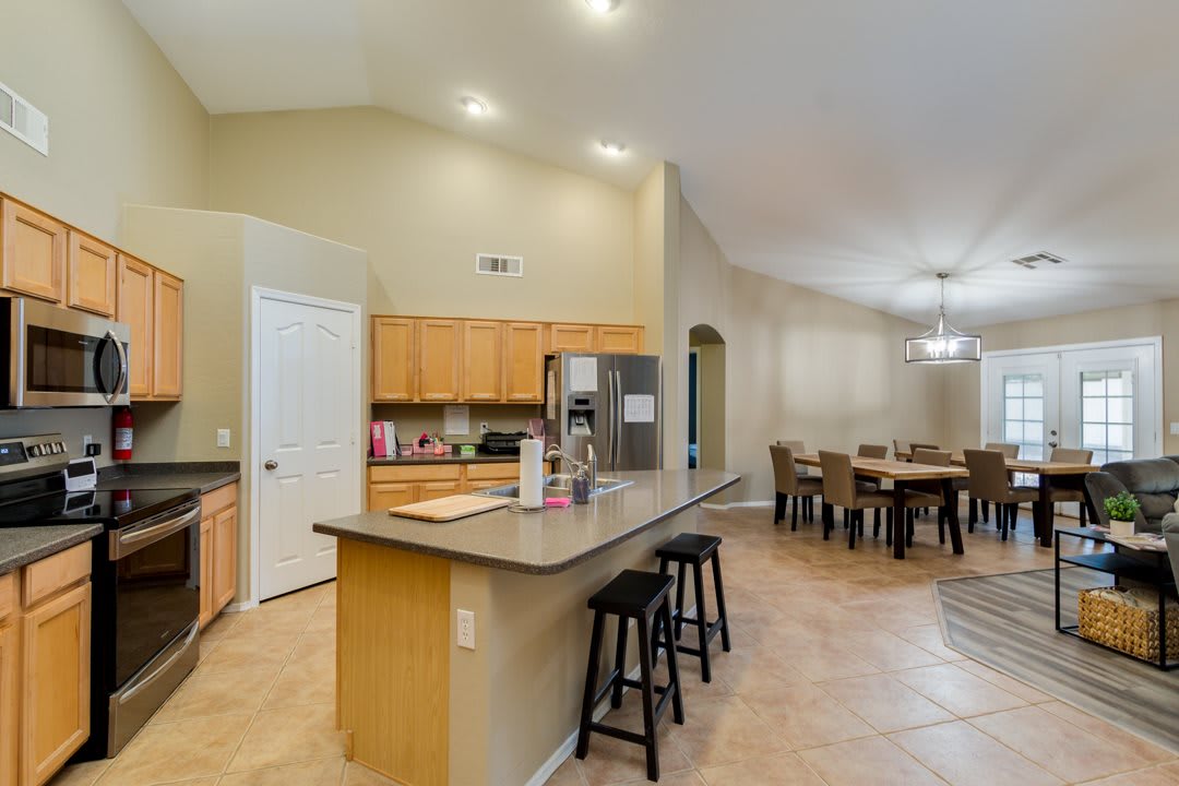 A spacious open floor plan featuring a kitchen with wood cabinets, an island with bar stools, and an adjacent dining area.