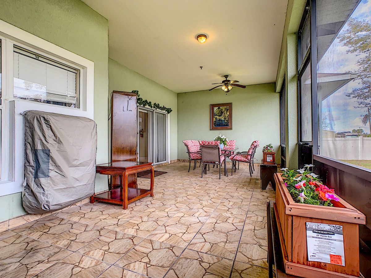 A cozy indoor patio featuring a dining table and chairs, surrounded by green walls and adorned with artwork and plants.