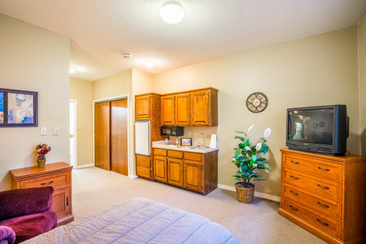 A cozy bedroom with wooden furniture and a small kitchenette area.