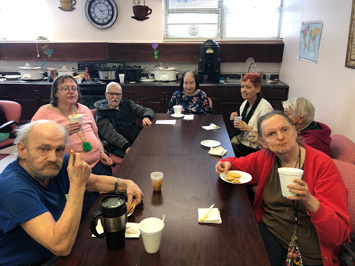 A group of seniors enjoying snacks and conversation around a table.