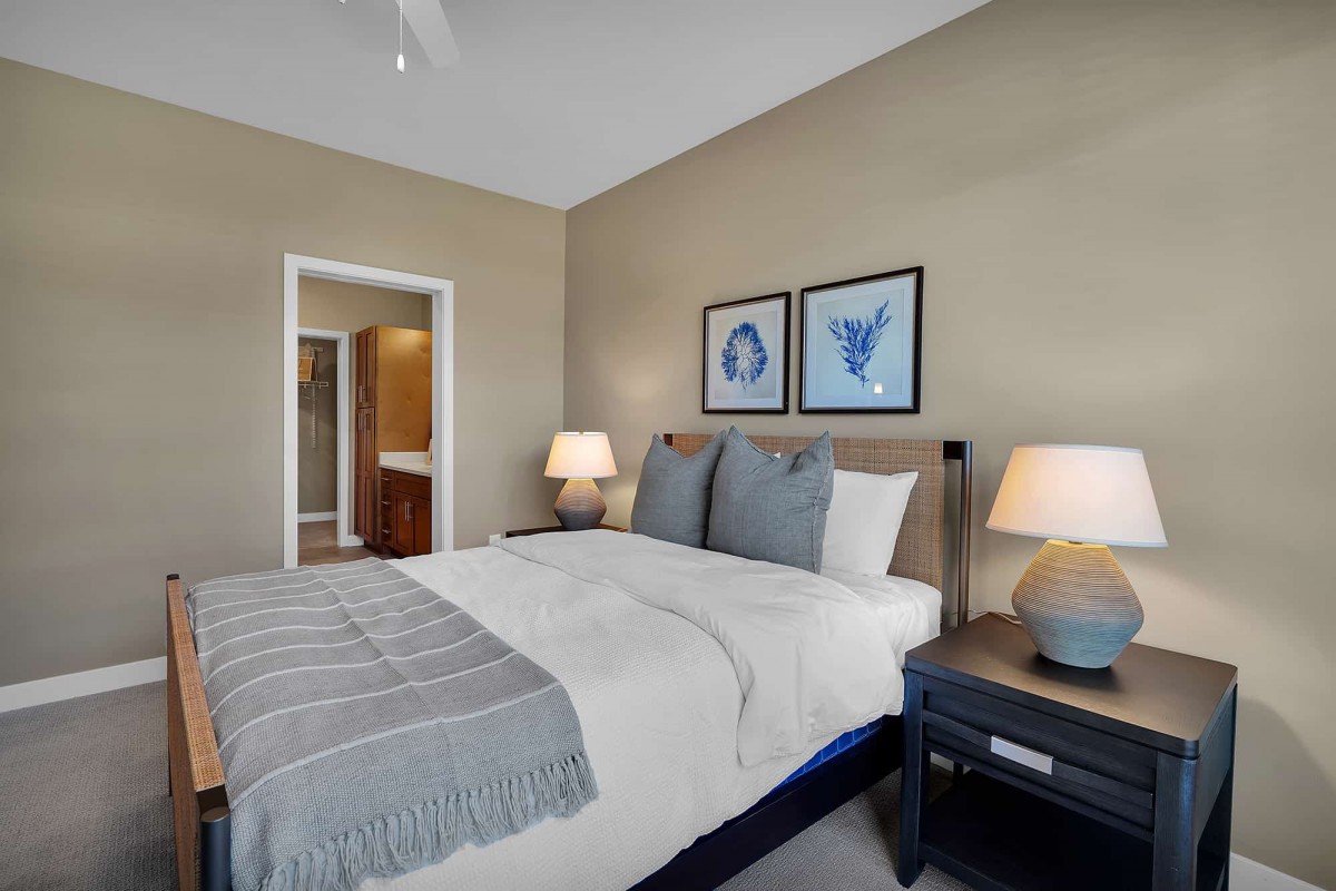 A cozy and well-decorated bedroom featuring a neatly made bed, nightstands with lamps, and framed artwork on the wall.
