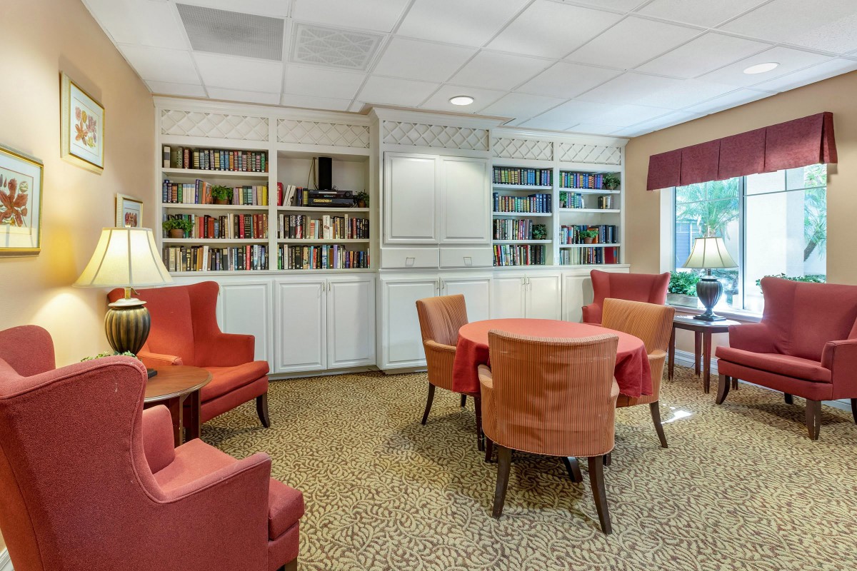 A cozy library room with bookshelves, comfortable chairs, and a round table.