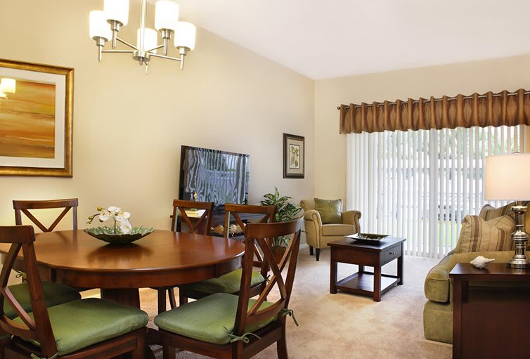 A cozy living and dining area featuring a wooden dining table with chairs, a comfortable seating arrangement with sofas and armchairs, and elegant window treatments.