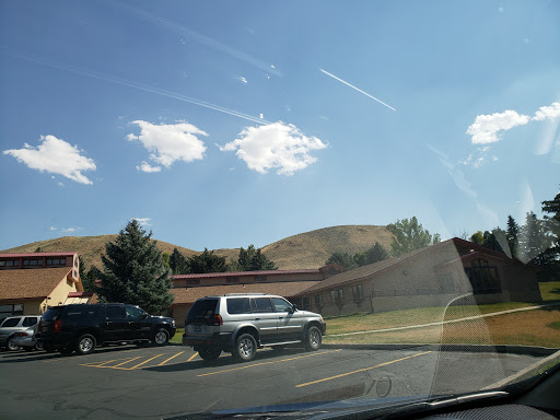 A sunny day with scattered clouds over a parking lot and rolling hills.