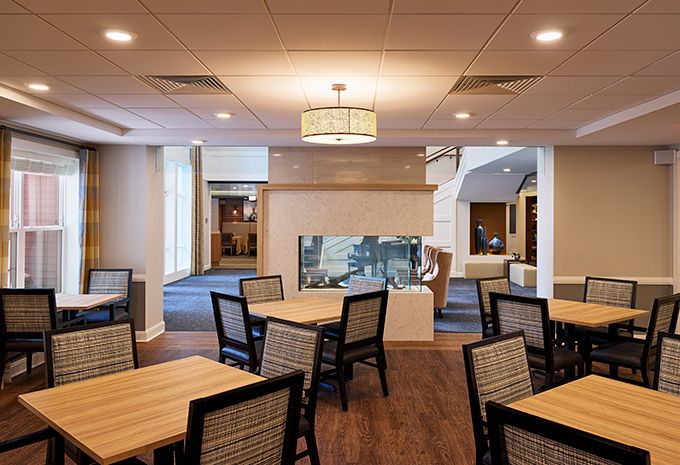 A modern dining area with neatly arranged tables and chairs, featuring stylish lighting fixtures.