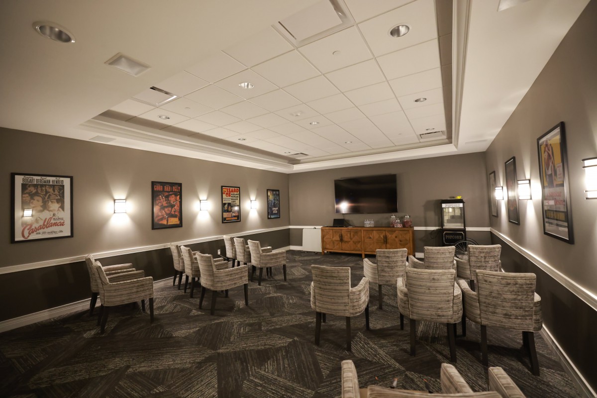 A conference room with chairs arranged around a television and decorated with wall art.