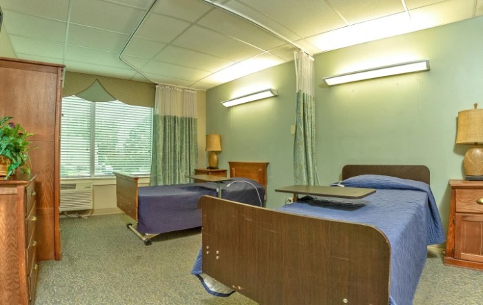 A hospital room with two beds and privacy curtains.