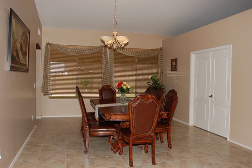 A dining room with a wooden table, chairs, chandelier, and decorative plants.