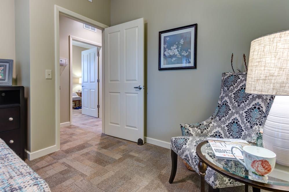 A cozy living room corner featuring a patterned chair, a small table, and framed artwork on the wall.