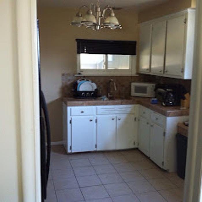 A compact kitchen with white cabinets, appliances, and a window above the countertop.