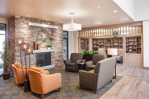A cozy lounge area featuring comfortable seating, a stone accent wall, and warm lighting.
