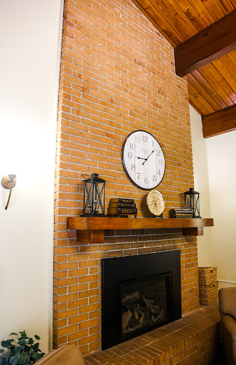 A cozy living room featuring a rustic brick wall with a clock and decorative lanterns above the fireplace.