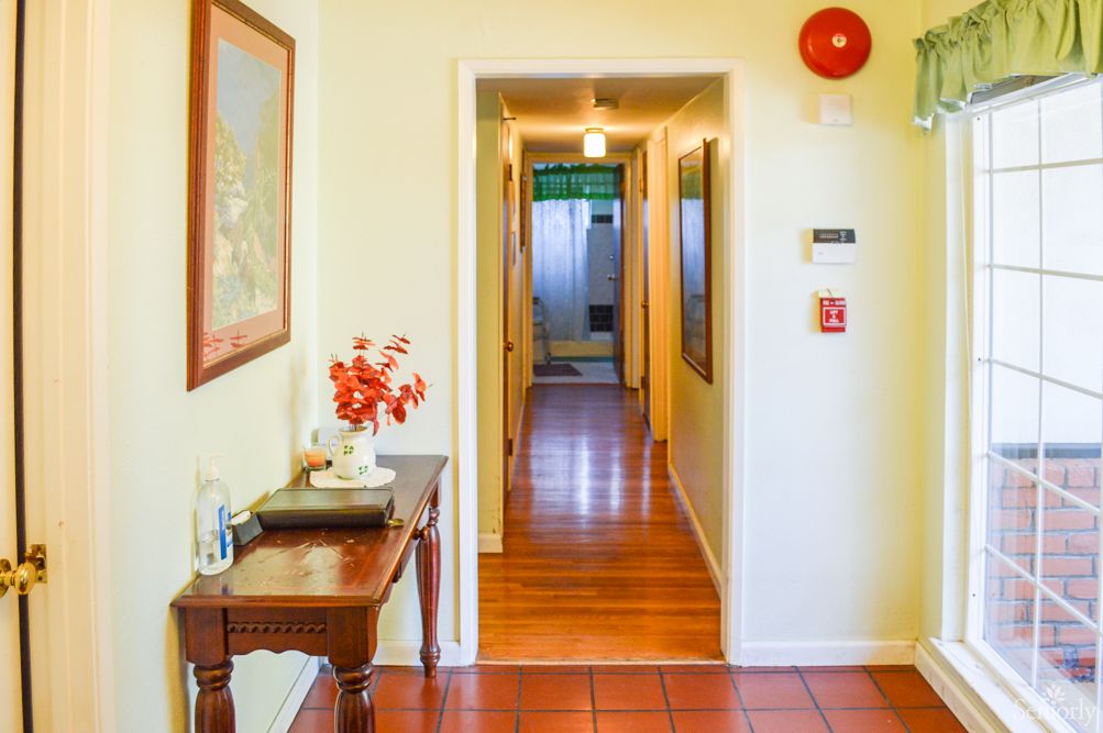 A well-lit hallway with wooden flooring and a decorative table on the side.