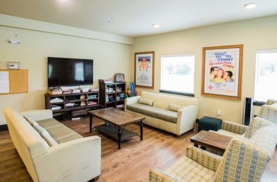 A cozy living room with sofas, a television, and colorful posters on the walls.