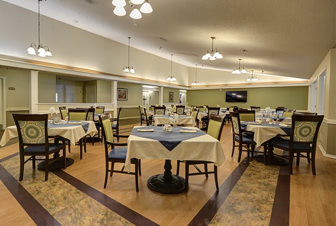 An elegant dining area with neatly arranged tables and chairs, featuring tasteful lighting fixtures.