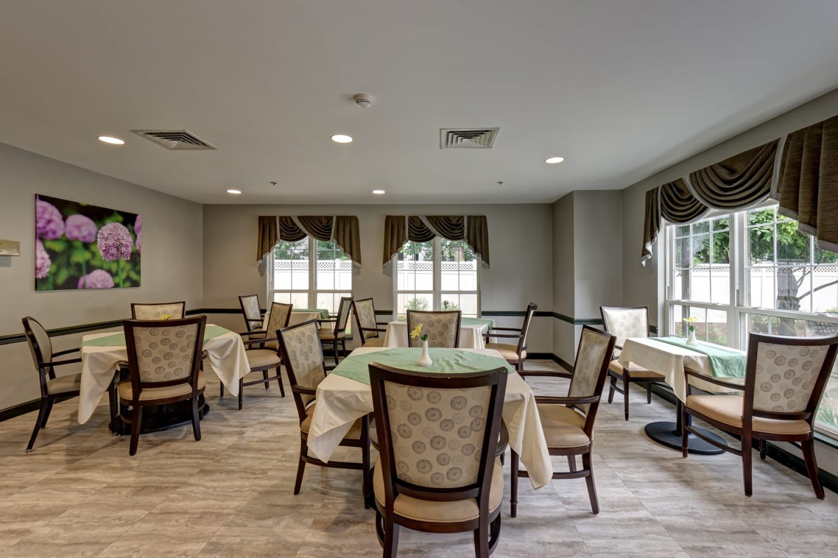 An elegant dining room with neatly arranged tables and cushioned chairs.
