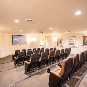 A cozy home theater room with tiered seating and movie posters on the walls.