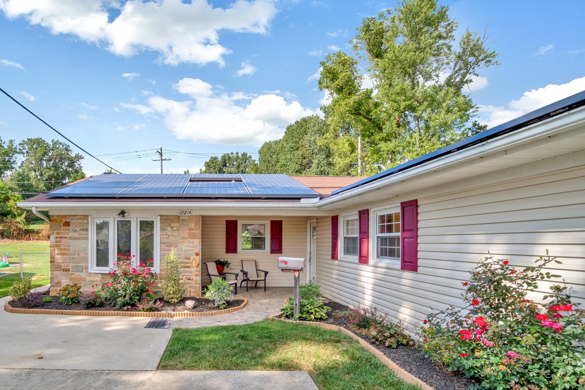 A suburban home with solar panels and a well-maintained front yard on a sunny day.