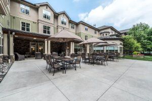 Outdoor patio area with tables and umbrellas in front of a residential building.