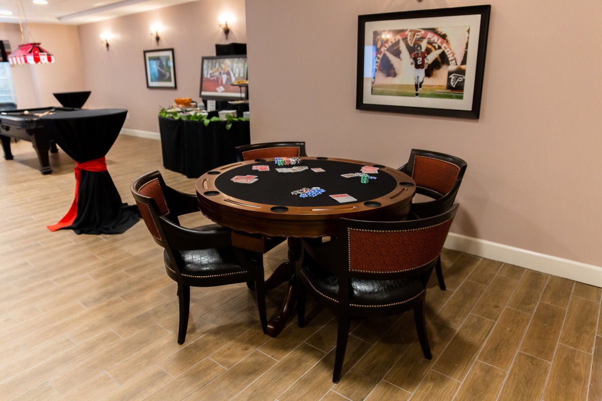 A poker table with chairs set up in a game room, featuring cards and chips ready for play.