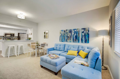 A contemporary living room featuring a stylish blue sectional sofa and vibrant artwork.
