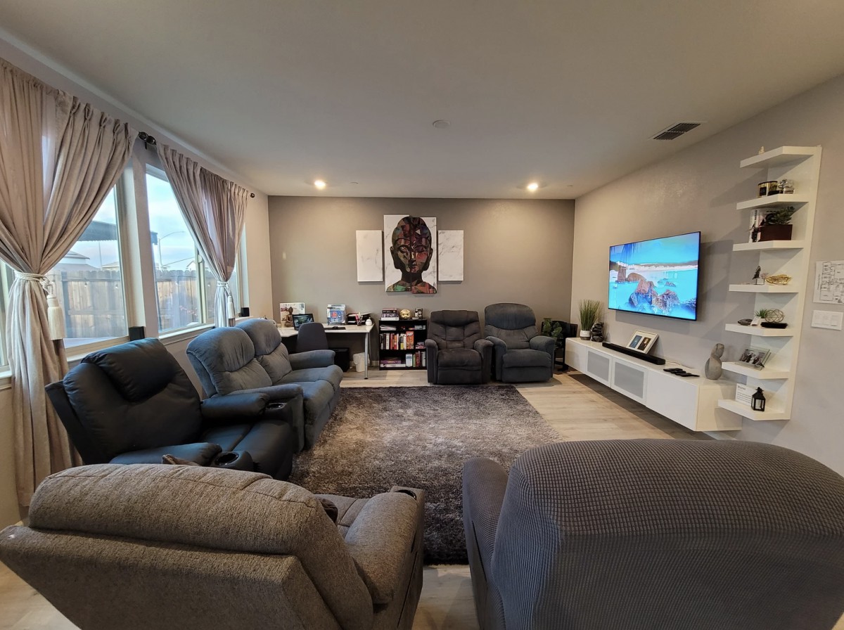 A cozy living room with a contemporary design featuring comfortable sofas, a large wall-mounted television, and elegant wall art.