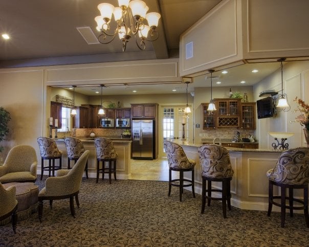 A spacious kitchen and dining area with bar stools, a chandelier, and a countertop.