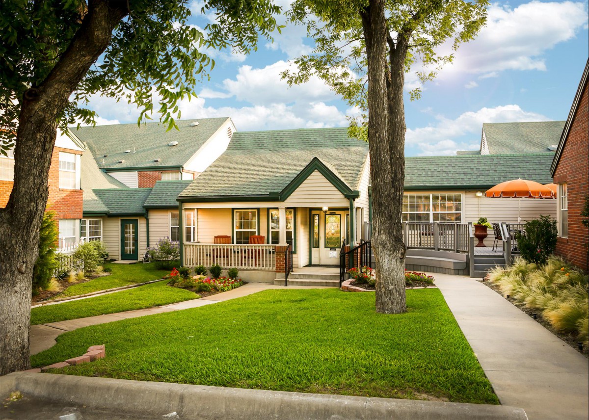 A charming suburban house with a well-maintained lawn and green roof.
