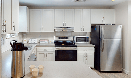 Modern kitchen with white cabinets and stainless steel appliances.