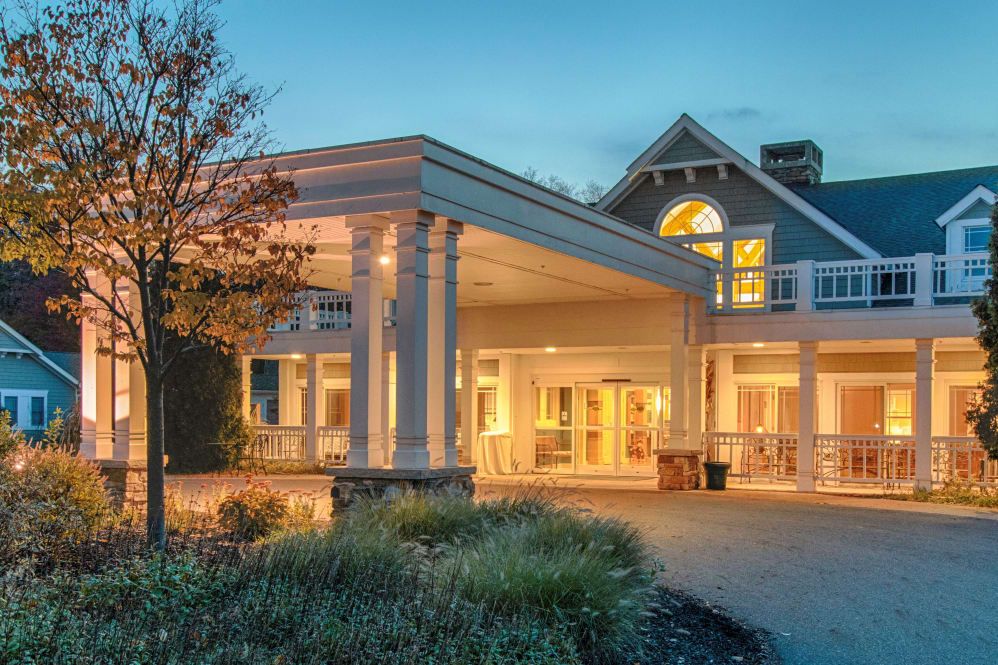 A beautifully lit building entrance in the evening with surrounding landscaping.