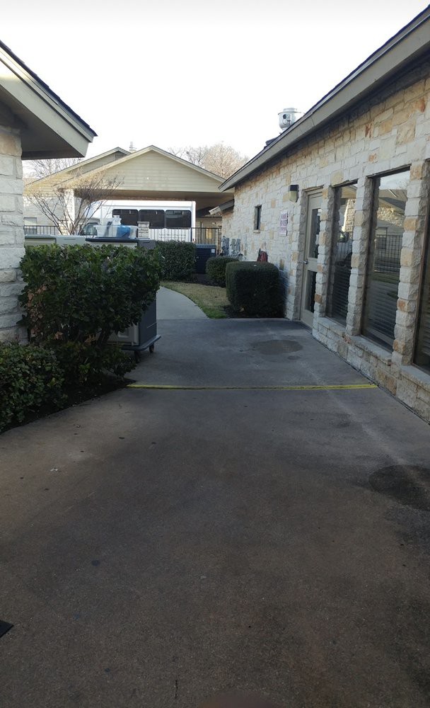 A pathway between two buildings with bushes lining the sides.
