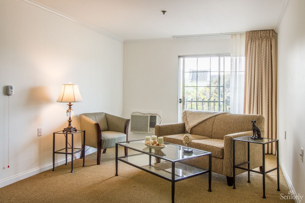 A cozy living room with a sofa, armchairs, and a coffee table near a window.