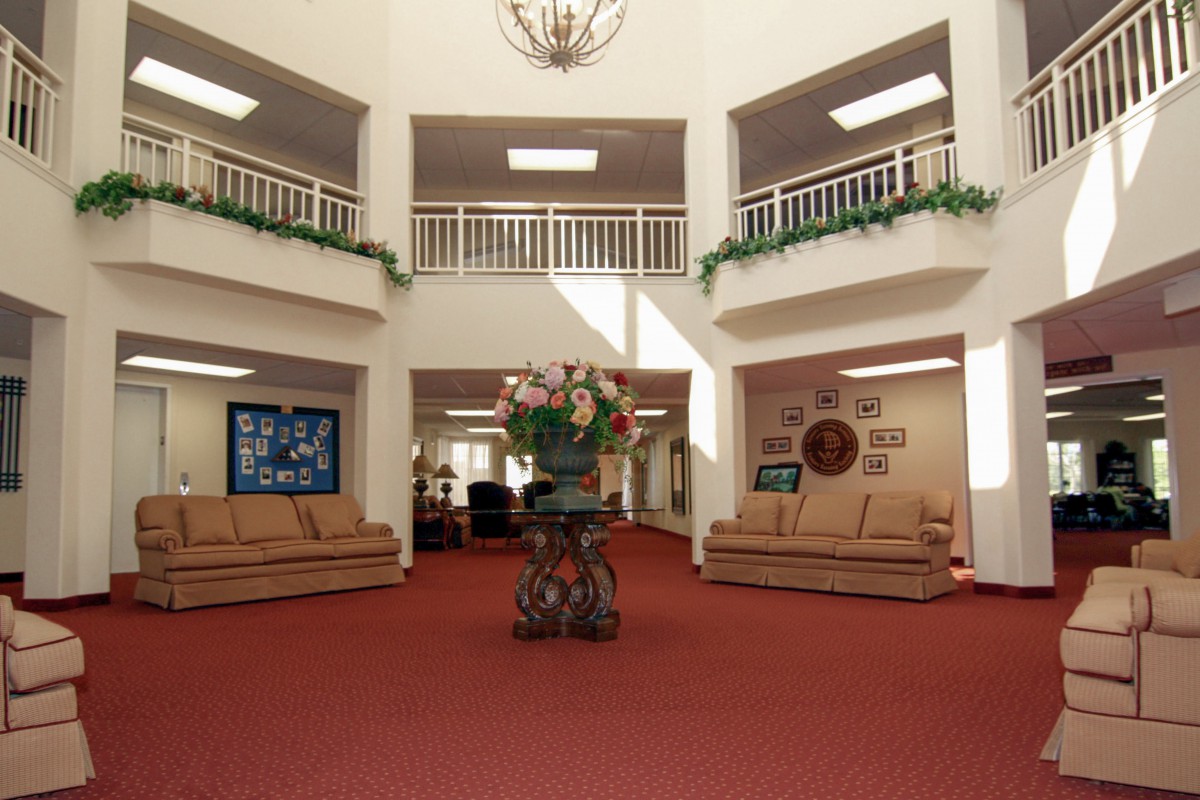 A spacious lobby with comfortable sofas and elegant decor, featuring a central floral arrangement.