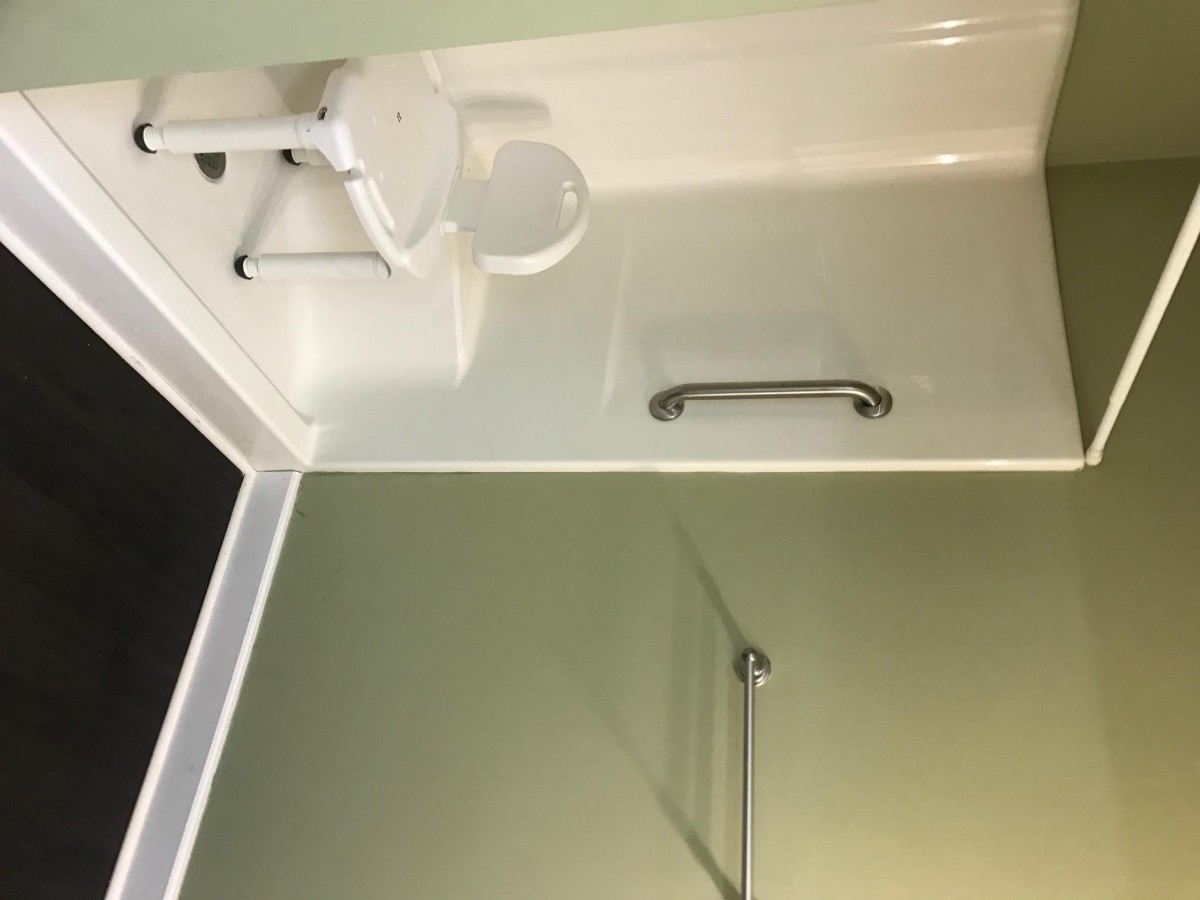 A compact bathroom with a sink, toilet, and grab bar.