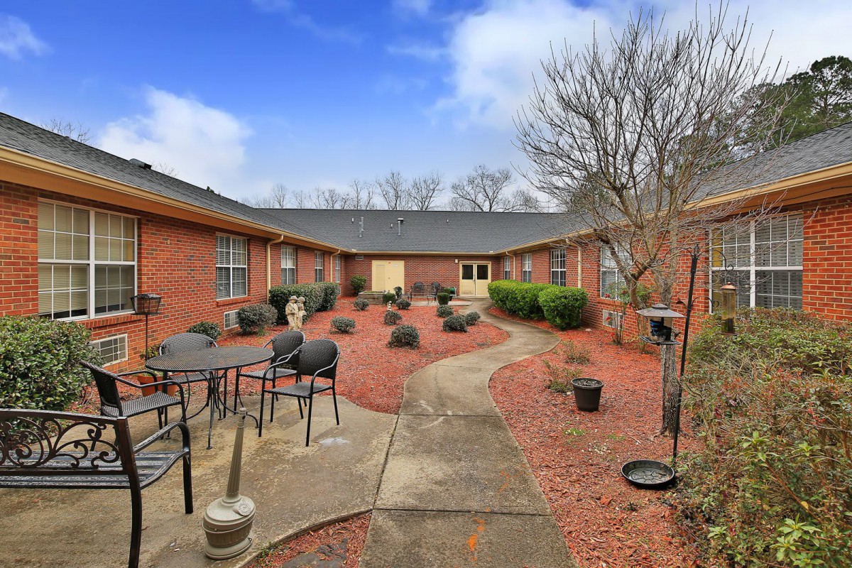 A cozy courtyard with outdoor seating surrounded by a brick building and landscaped garden.