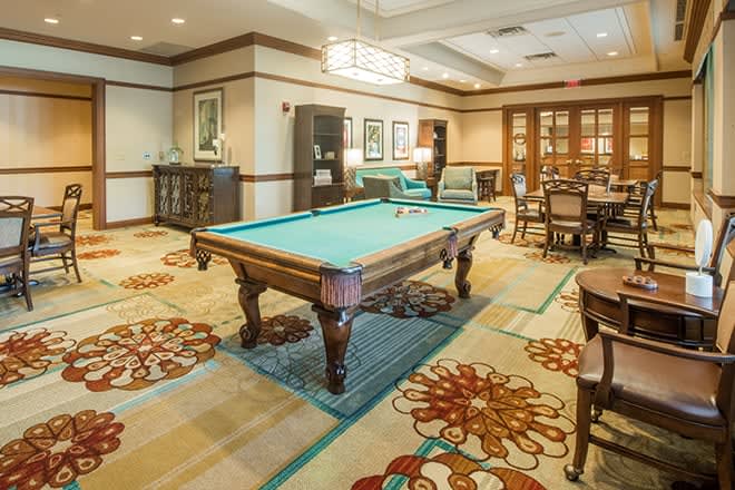 A spacious game room featuring a billiard table and comfortable seating.