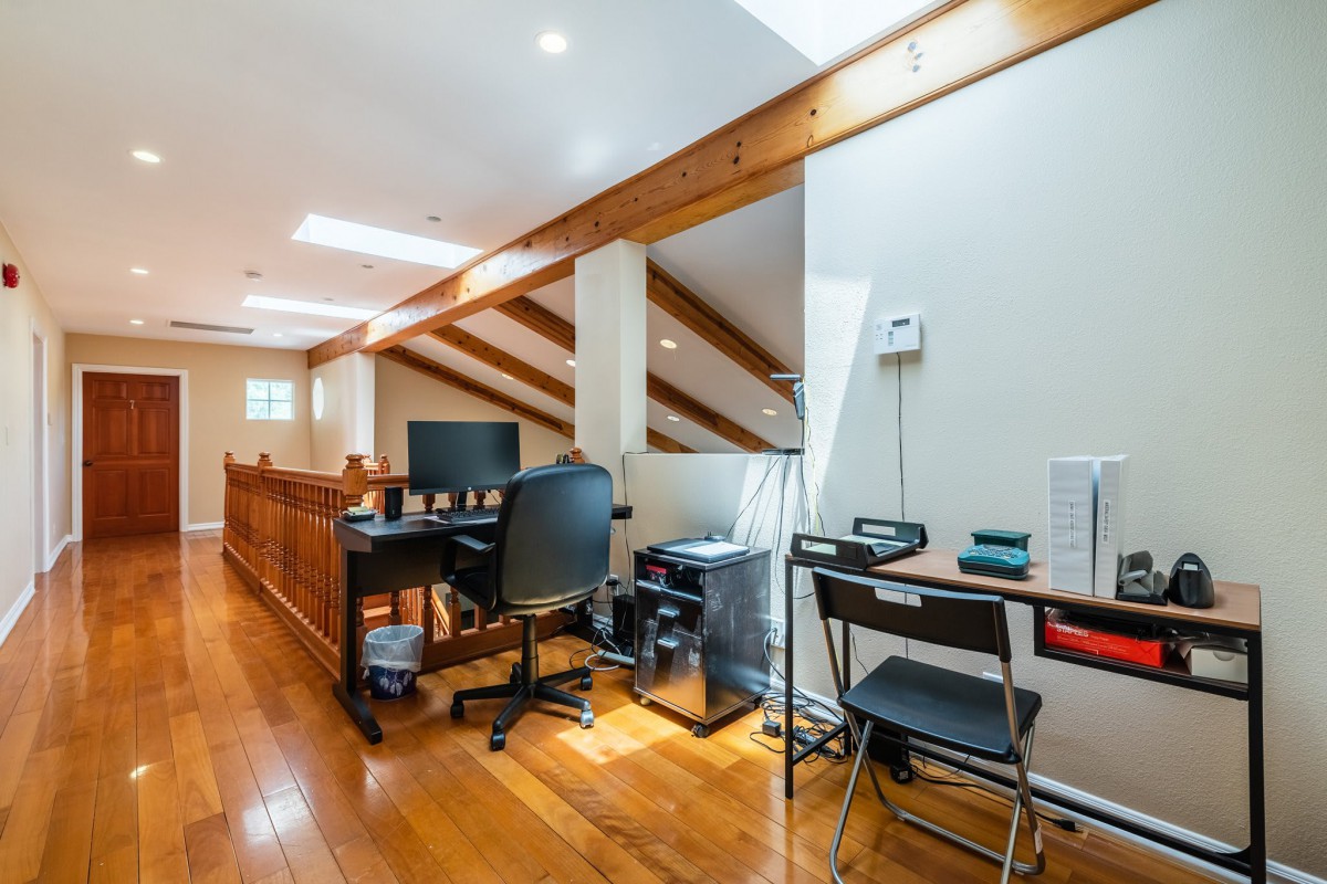A cozy loft home office with wooden beams and ample natural light.