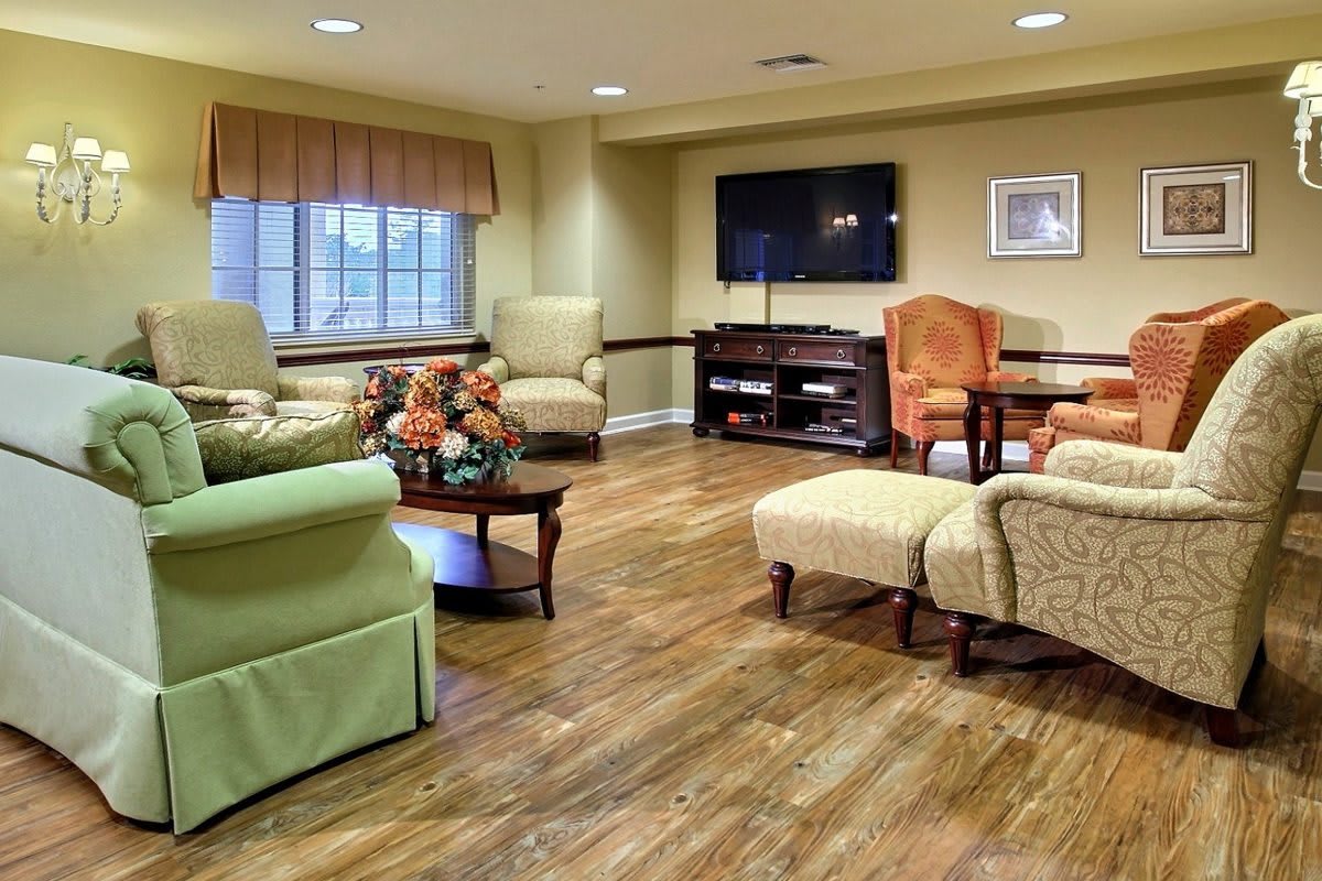 A cozy living room with comfortable seating, a television, and a wooden floor.