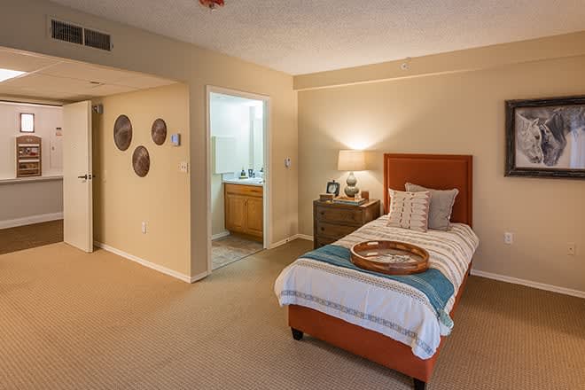 A cozy bedroom with a single bed, bedside lamp, and simple decor.