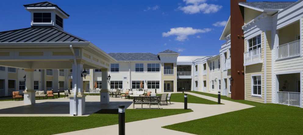 A sunny view of a modern building with a central courtyard featuring outdoor seating and pathways.