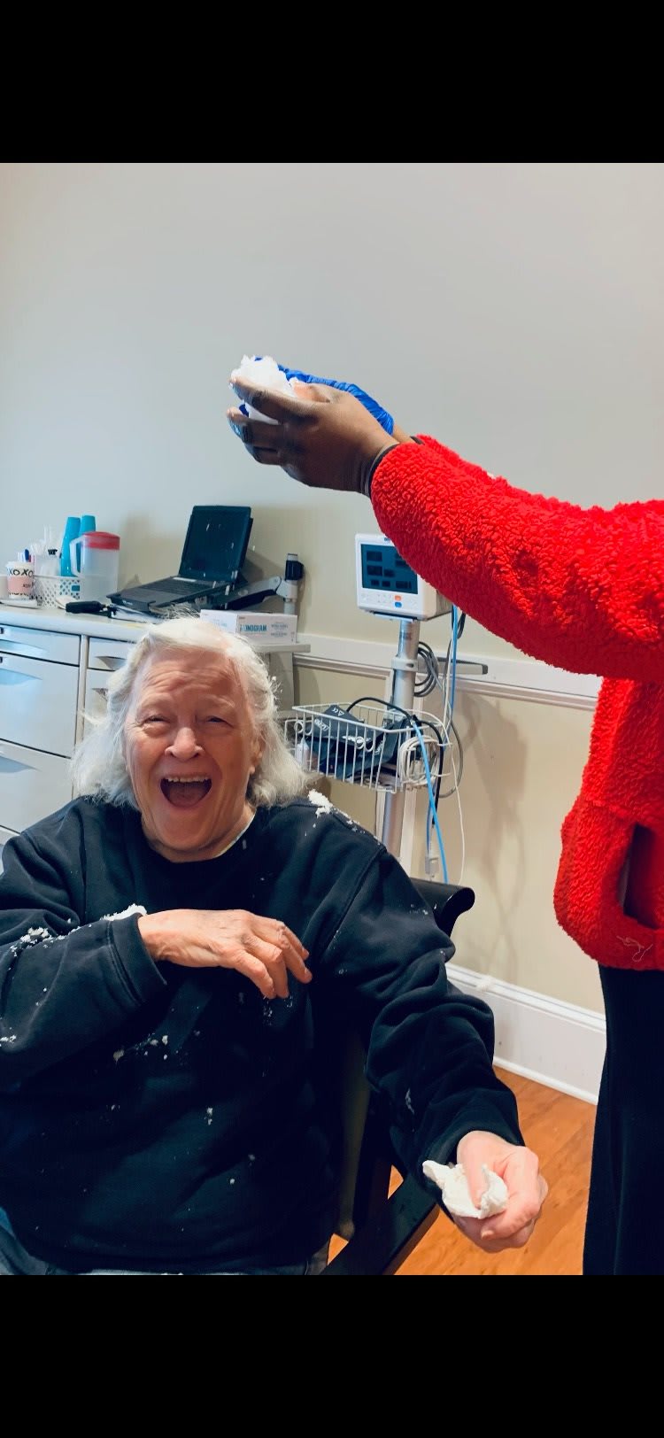 An elderly person laughing joyfully during an interaction in a healthcare setting.