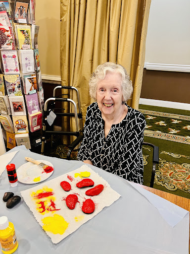 An elderly woman enjoys a colorful art activity, showcasing her creative side.