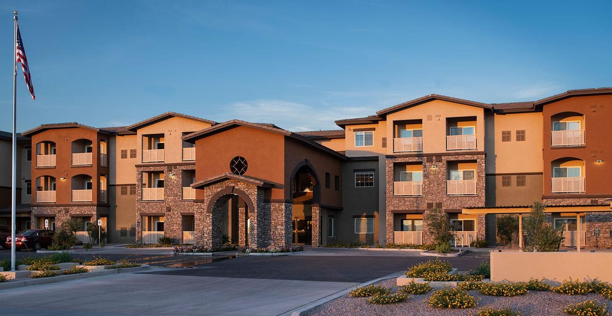 A modern three-story hotel building with a welcoming entrance and landscaped surroundings in the evening.