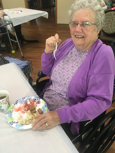 An elderly woman enjoying dessert at a social gathering.