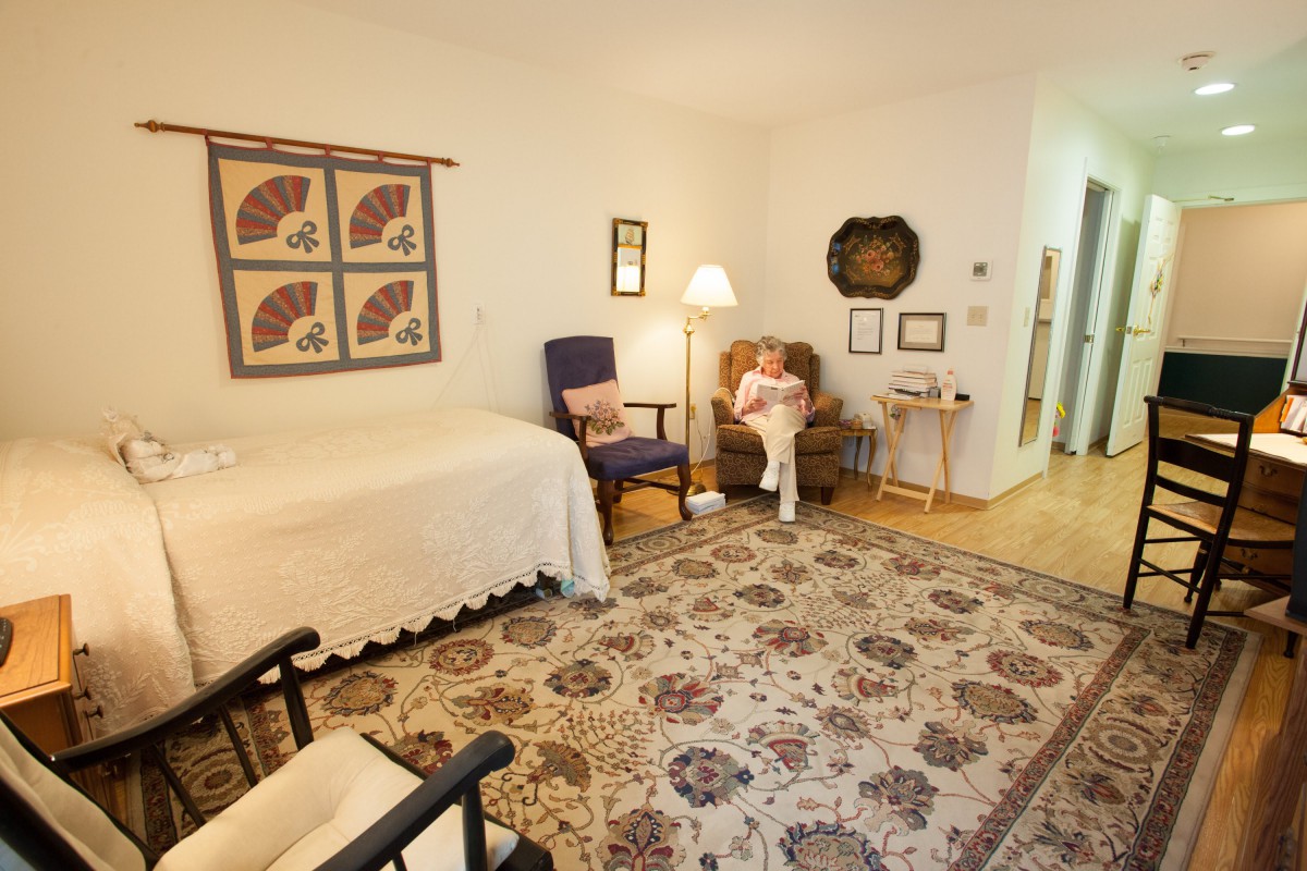 A cozy living room with traditional decor, featuring an area rug, armchair, and wall art.