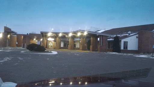 A hotel entrance captured during the evening, showcasing warm lights and a quiet parking area.