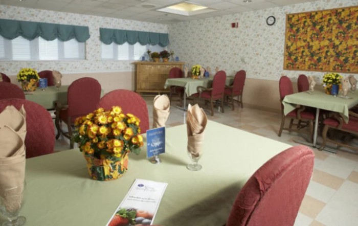 A cozy dining room with tables set with flowers and napkins.