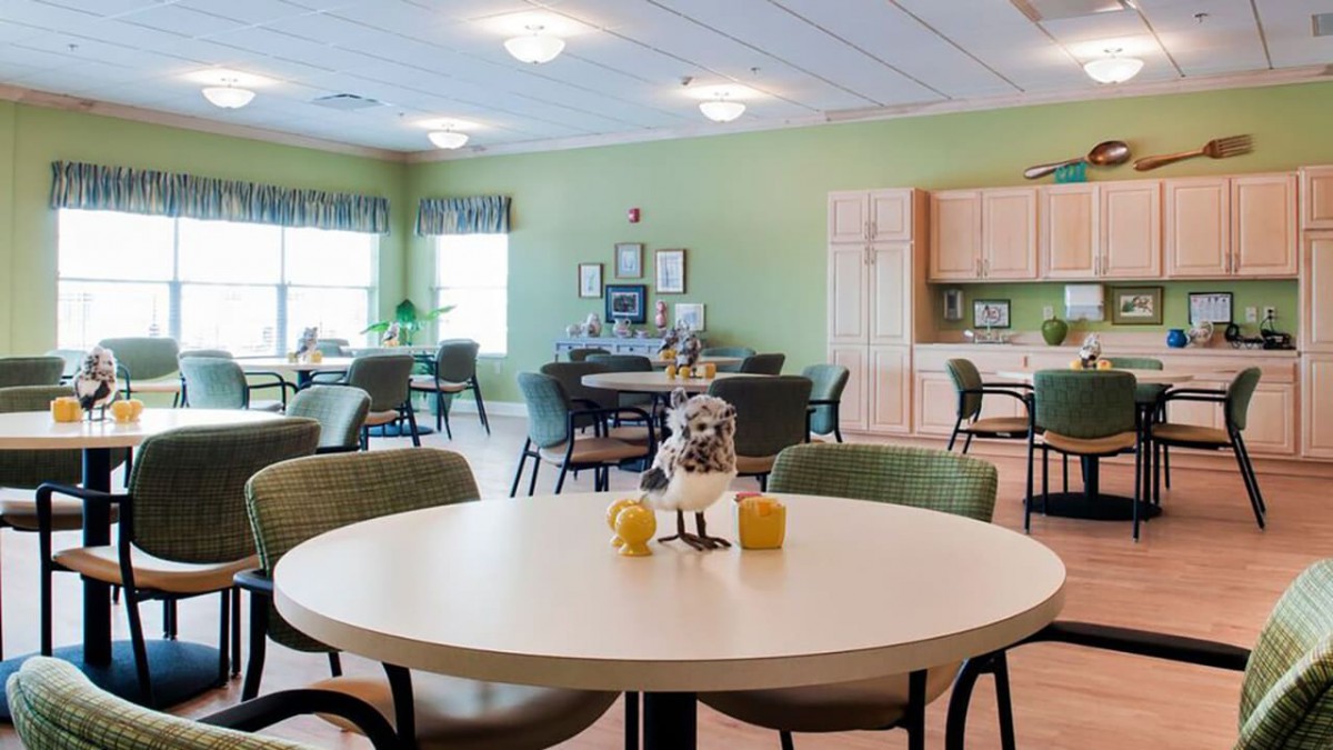 A well-lit dining area with tables and chairs, featuring a cozy kitchen space.